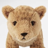 Soft, plush teddy bear resembling a lion cub, featuring detailed embroidered eyes and nose, sitting upright against a white background.
