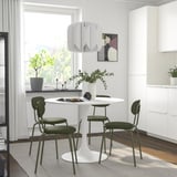 Modern dining area with white DOCKSTA table and green chairs, minimalist design, perfect for small spaces.