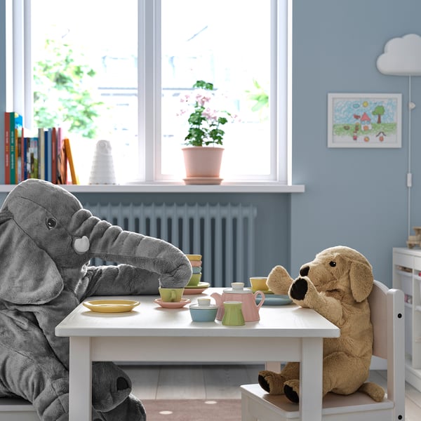 Childs tea party setup with elephant & dog plush toys, books, & plants.