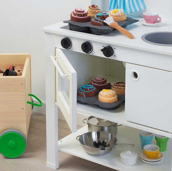 Toy kitchen play set with oven, pots, cups, and fake food.