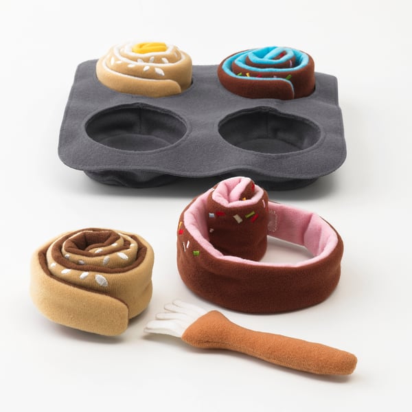 A toy baking set with a tray and plush buns. The buns are designed to be rolled and brushed, promoting pretend play and fine motor skills.