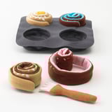 A toy baking set with a tray and plush buns. The buns are designed to be rolled and brushed, promoting pretend play and fine motor skills.