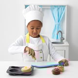 Child pretends to frost toy buns with brush.