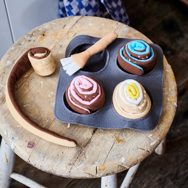 Playful DUKTIG toy bakeware with colorful fabric buns on worn round table.