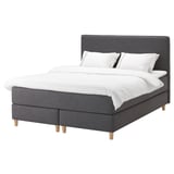 A DUNVIK bed in grey with a soft headboard, white linens, and wooden legs.