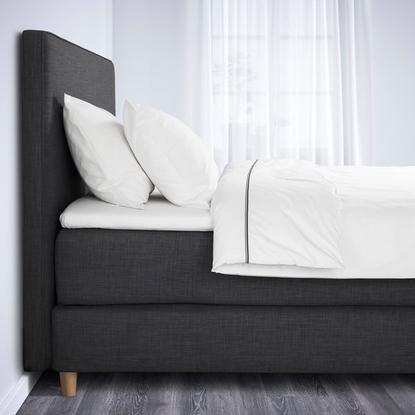 Bed with gray upholstered headboard and white linens, showcasing a soft, inviting look.