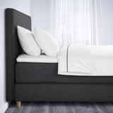 Bed with gray upholstered headboard and white linens, showcasing a soft, inviting look.