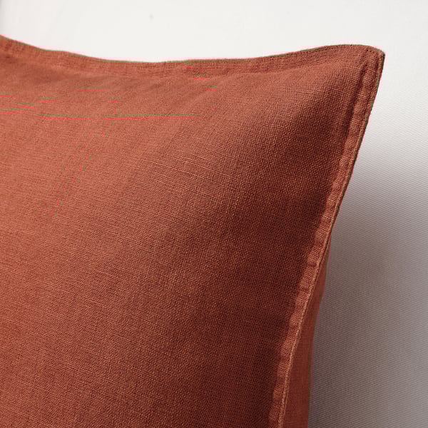 Close-up of a soft, reddish-brown linen cushion cover with a hidden zipper, showcasing its smooth texture.