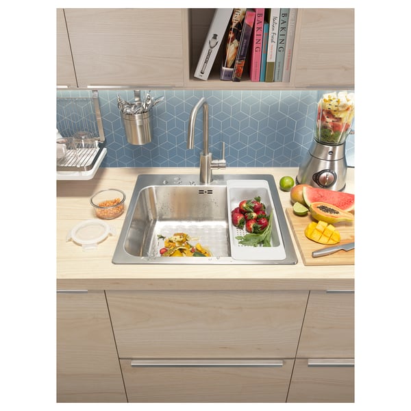 Kitchen sink placed in wooden countertop with fruits.