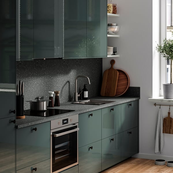 Teal EKBACKEN kitchen countertop, sink, oven, dark appliances, wood decor.