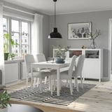 Modern dining room with white EKEDALEN table, gray chairs, plant, dishes, striped rug, lamp, and framed photo.