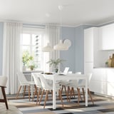 Modern dining room with white EKEDALEN extendable table and chairs, surrounded by white pendant lights and tall windows with white curtains.
