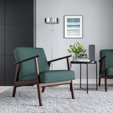 Cozy living room with two green EKENÄSET armchairs, side table, flowers, and retro beach art.