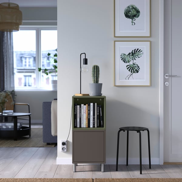 Modern living room with green EKET storage, cactus, lamp, art, and blue sofa.