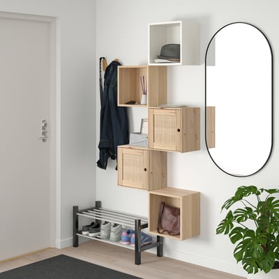 Modern entryway with asymmetric light wood EKET shelves, black coat hook, and shoe rack. Round mirror, green plant, and black mat.