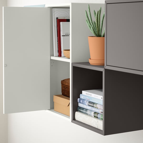 Wall-mounted shelves with a potted plant and books on display. One cabinet door is open, revealing organized books and a wicker basket.