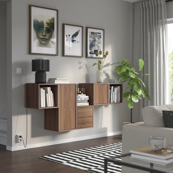 Modern living room with EKET storage, mixed wood cabinets, plants, gray curtains, and cozy sofa.