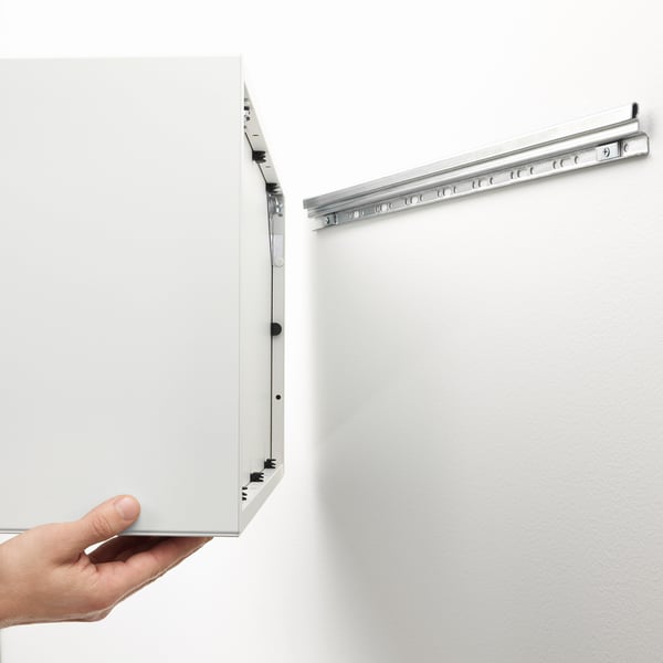 Hand holding EKET cabinet, demonstrating wall-mounted storage functionality with suspension rail.