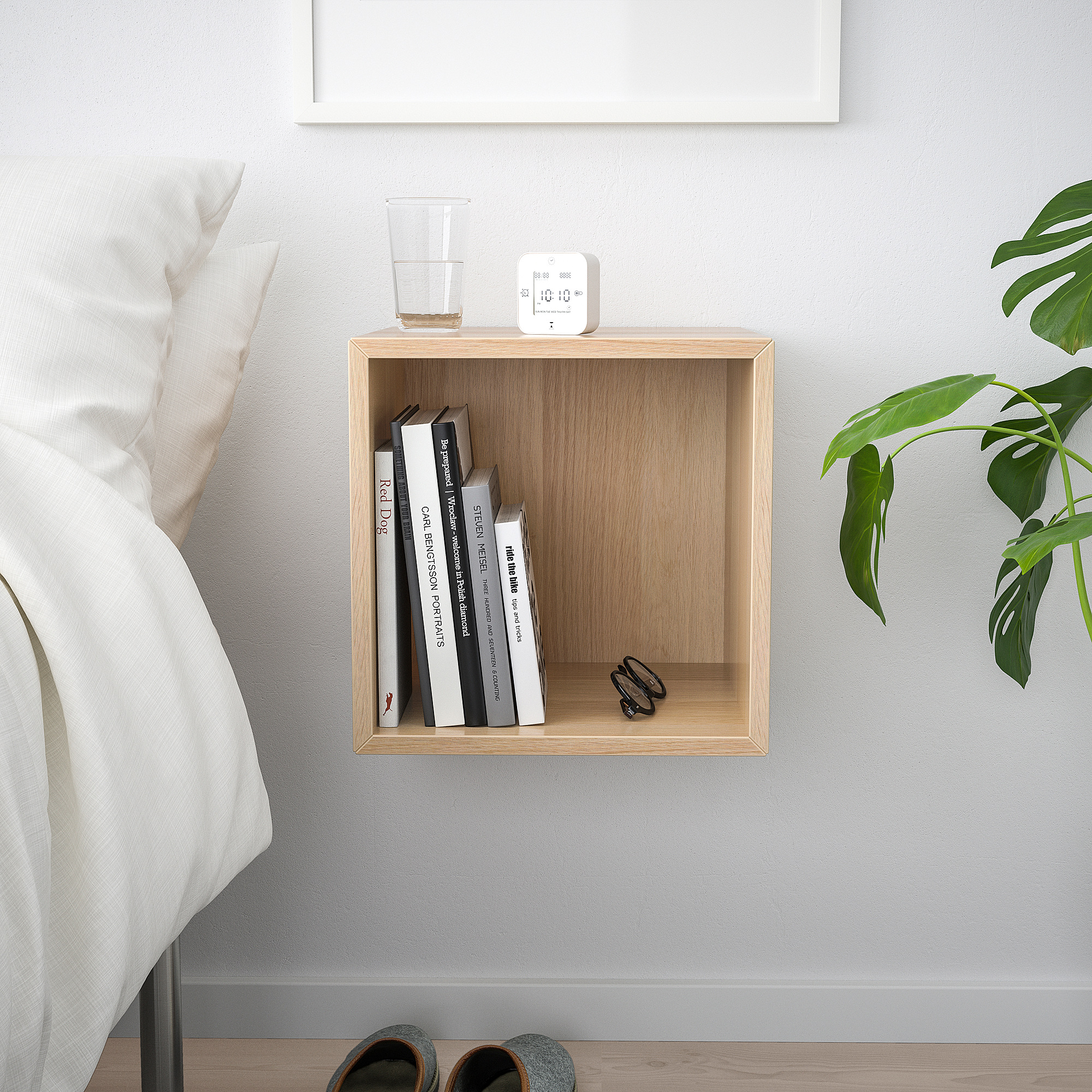 Wall-mounted EKET storage cabinet in light wood with books, glass, and clock.