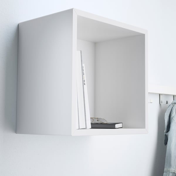 A wall-mounted cube shelf, part of the EKET system, stores books and holds items on its shelf.