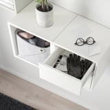 Wall storage with bins, open drawer, and plant.