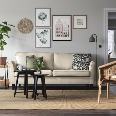 Cozy living room with EKHOLMA sofa, green pillows, coffee table, plant, floor lamp, and wall decor.