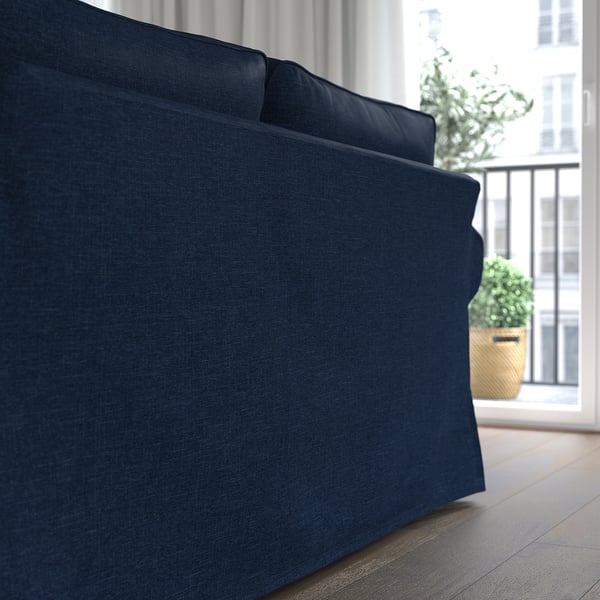 Dark blue upholstered sofa with cushions, placed near a window.