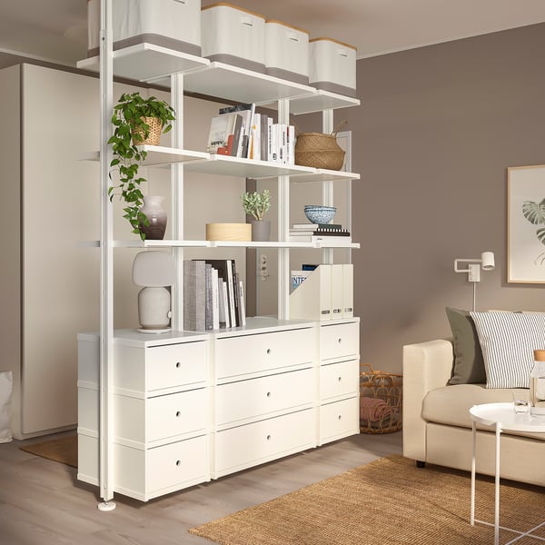 ELVARLI storage unit with books, vases, and a plant. Beige sofa and woven basket nearby.