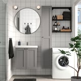 Modern bathroom with grey ENHET storage, mirror, and white washing machine. Tidy, minimalist design.