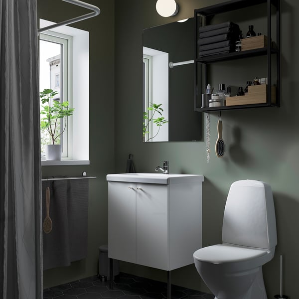 Clean, modern bathroom with white ENHET vanity and toilet. Green walls, mirrored cabinet, and hanging plants by window.