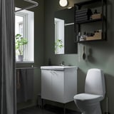 Clean, modern bathroom with white ENHET vanity and toilet. Green walls, mirrored cabinet, and hanging plants by window.