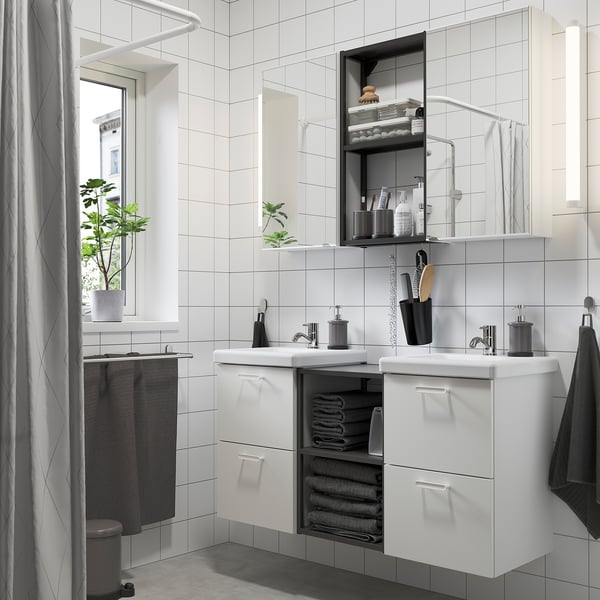 Modern bathroom with white ENHET vanity, mirror cabinets, and open shelves. Includes sinks, towels, and plants. Symmetrical design for shared space.
