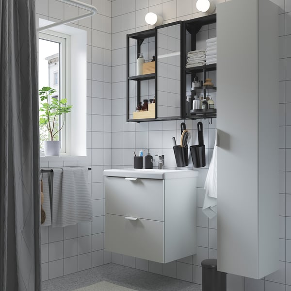ENHET bathroom setup with white cabinet, mirror, black accents and grey tiles. Compact design, neat and modern.