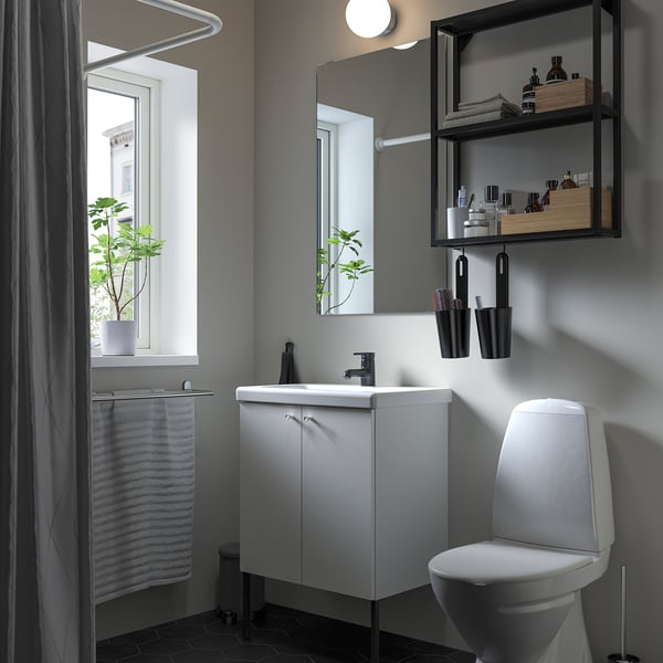 Modern bathroom with ENHET white cabinet, mirror, and toilet. Black accessories and plants. Sleek and minimalist design.