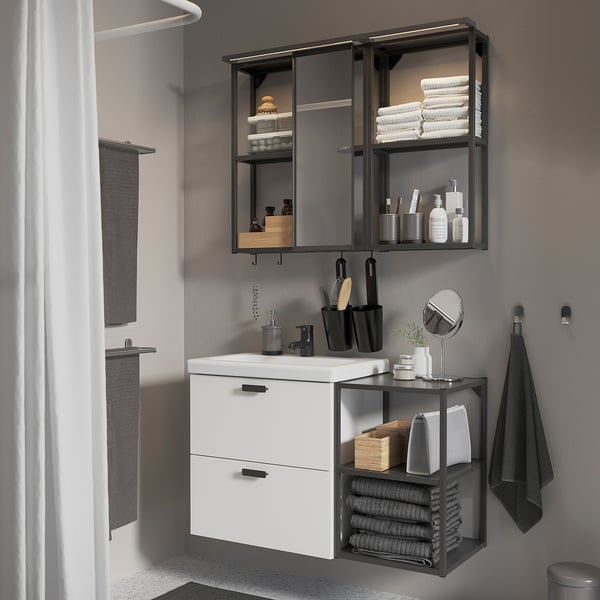 Modern bathroom with white cabinet, mirror, and storage shelves; black accents and accessories.