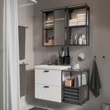 Modern bathroom with white cabinet, mirror, and storage shelves; black accents and accessories.