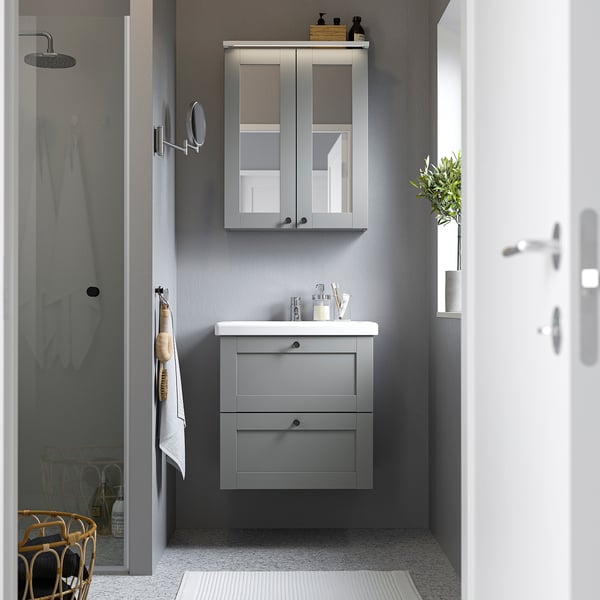 Modern bathroom with grey ENHET vanity. Sink, mirror cabinet, plant, towels, shower. Compact yet functional.