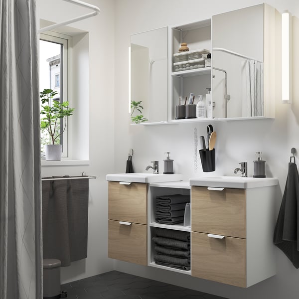 Modern bathroom with ENHET double vanity. Light wood, two sinks, mirrors, plants, and black accents.