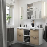 Modern bathroom with ENHET double vanity. Light wood, two sinks, mirrors, plants, and black accents.