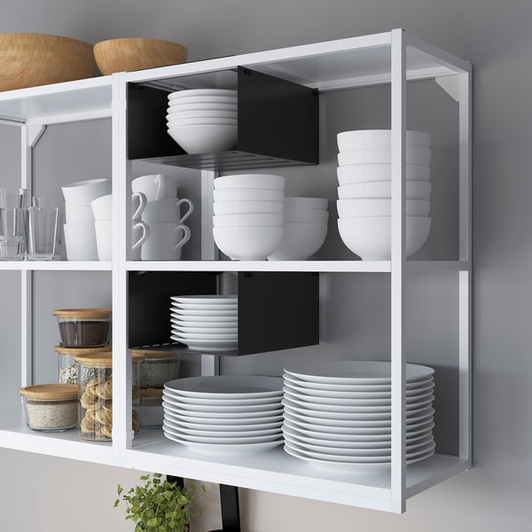Shelf with white plates, bowls, and cups neatly organized inside. Upper divided shelves keep items separate.
