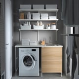 Modern laundry nook with ENHET white unit, wooden cabinet, sink, and open shelves.