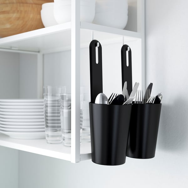 Black ENHET storage containers hang on rail, storing utensils next to kitchen shelves.