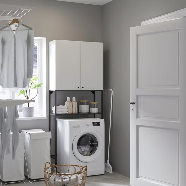 Modern, compact laundry setup with ENHET white cabinets and washer, neatly organizing space behind door.
