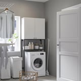 Modern, compact laundry setup with ENHET white cabinets and washer, neatly organizing space behind door.