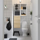 Modern bathroom: white toilet, black stool, gray towels, mirrored cabinet, black accents.