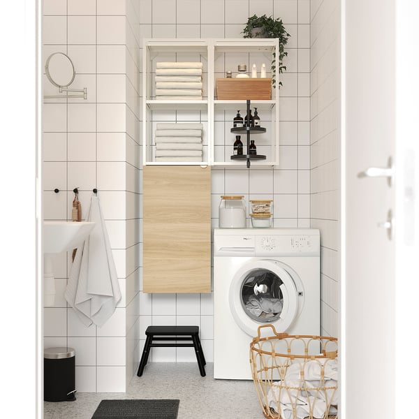 Modern bathroom with white ENHET shelves and laundry machine, light wood accents, clean decor, and wicker basket.