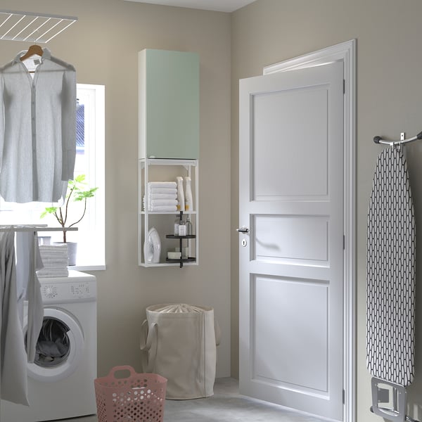 Modern laundry room with pale green ENHET storage unit, towels, cleaning supplies, washing machine, folded clothes, and laundry basket.