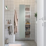 Green shelves with towels and toiletries beside sink.