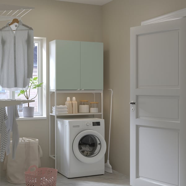 Modern laundry with green ENHET cabinet, white machine, neat shelves, beige walls, red basket.