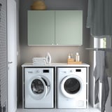 Modern laundry setup: grey-green ENHET cabinet over white washer/dryer, with storage and countertop for laundry items.